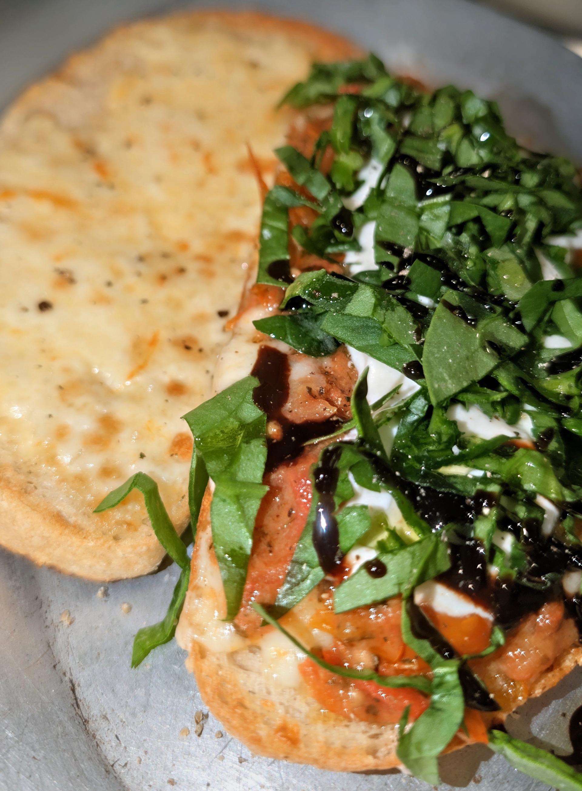 Close up of sourdough toast with whipped ricotta, tomato confit, shredded spinach and a balsamic drizzle