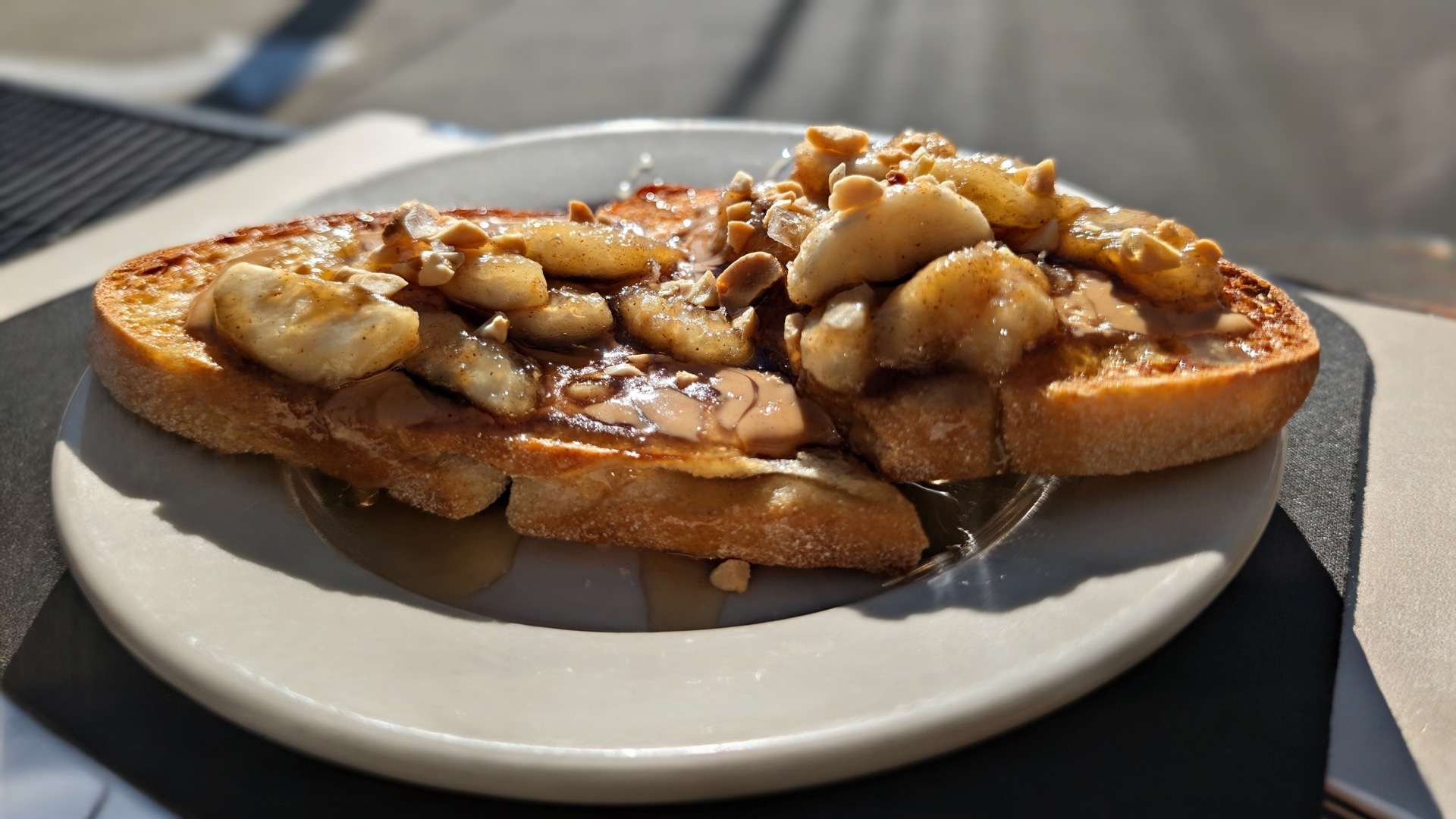 Sourdough toast piled with caramelized banana slices, crushed peanuts and maple syrup