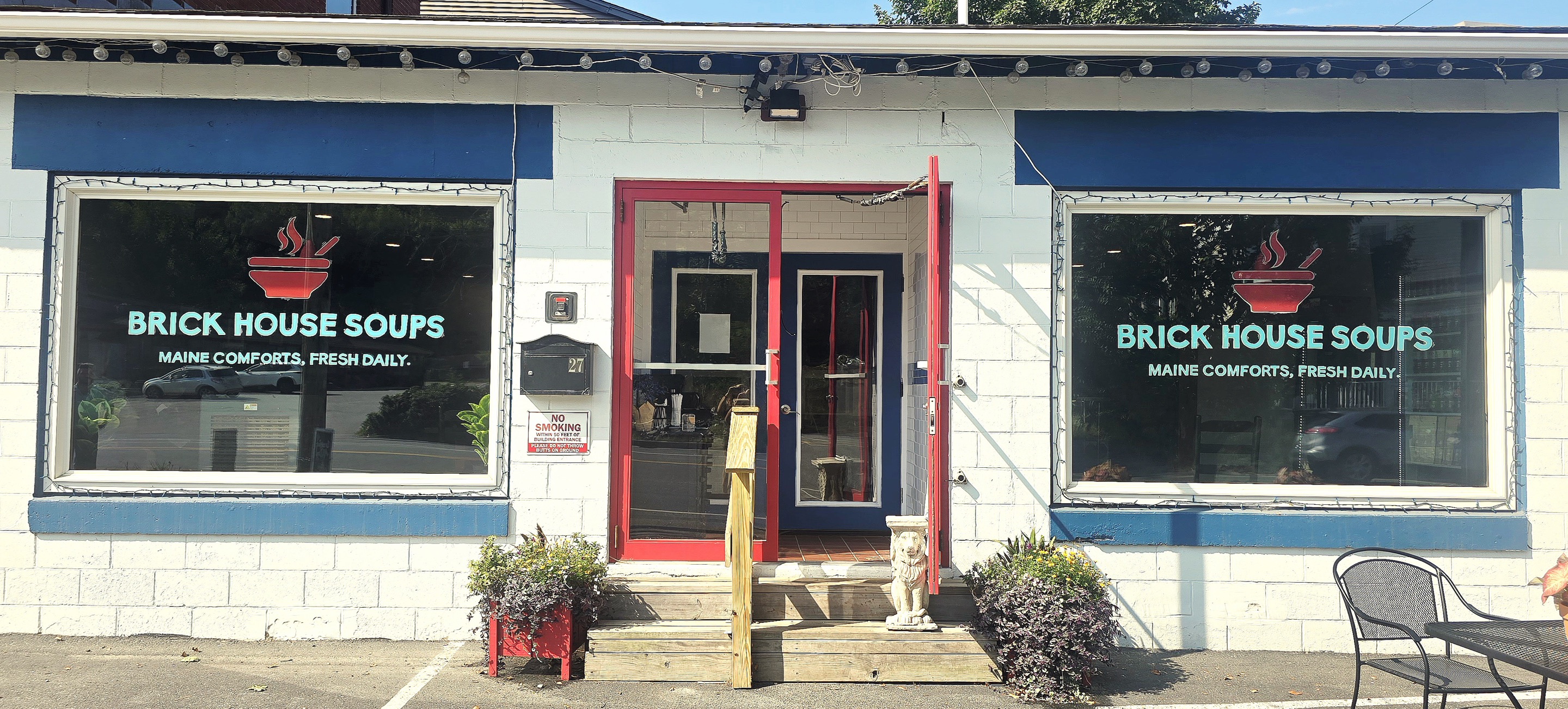The Brick House Soups storefront: white-painted block walls with blue trim, a red door and the logo lettered on both front windows